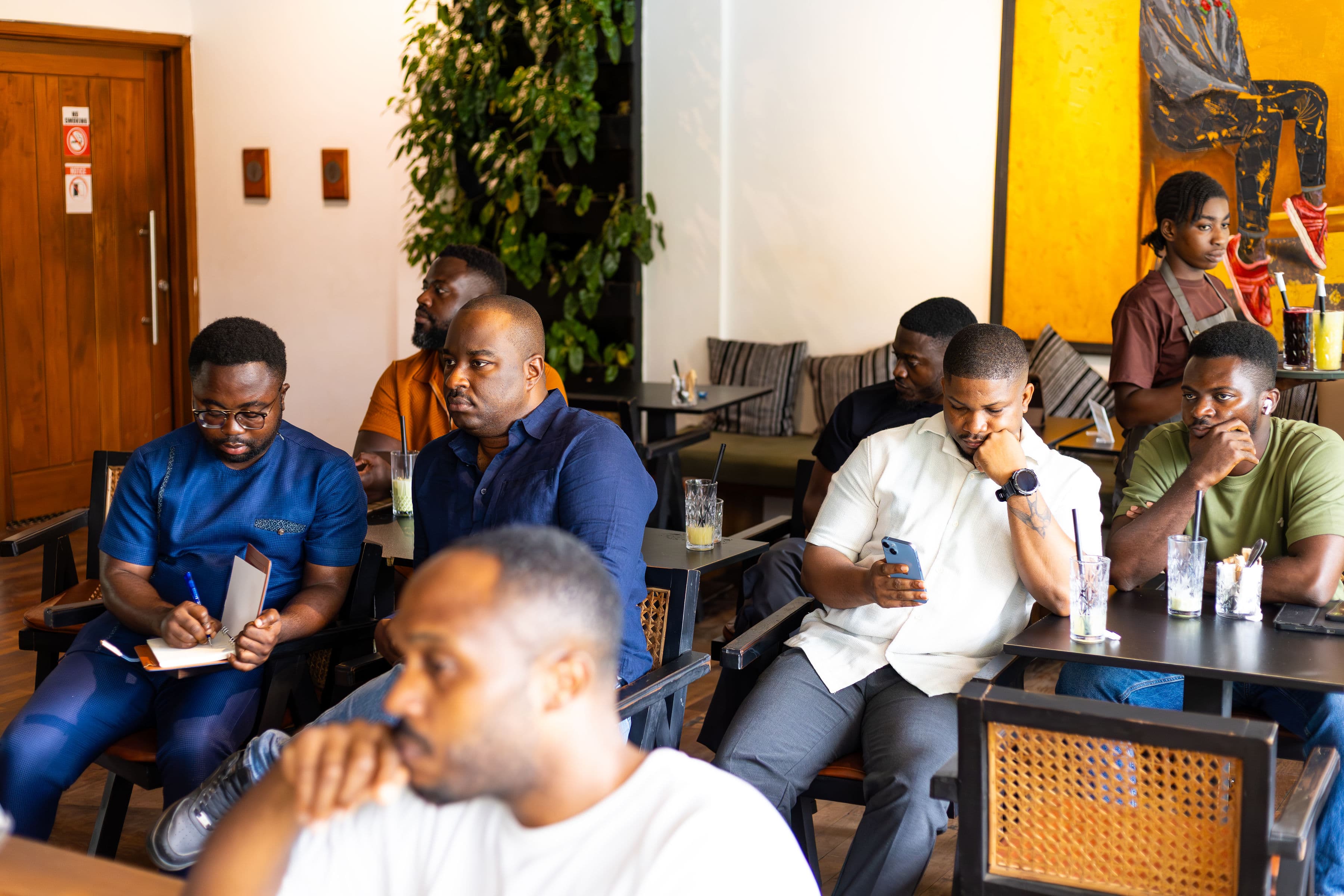 Attendees listening attentively, one taking notes in a journal