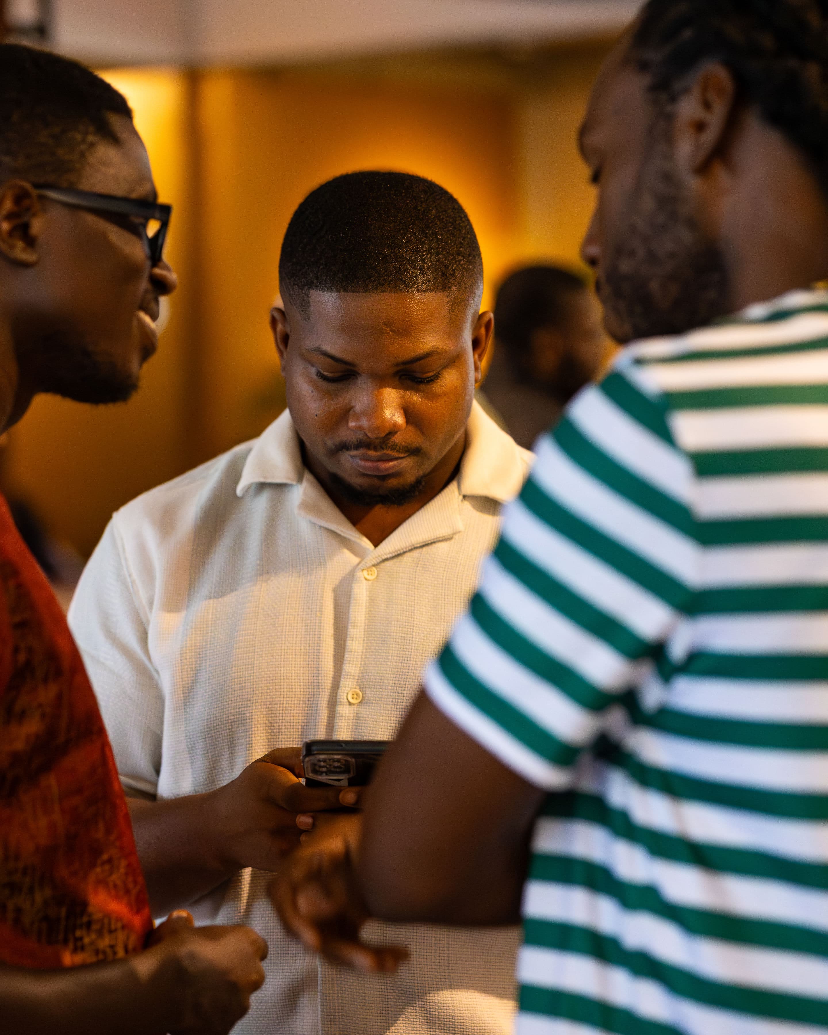 Three attendees in close conversation, sharing something on a phone screen