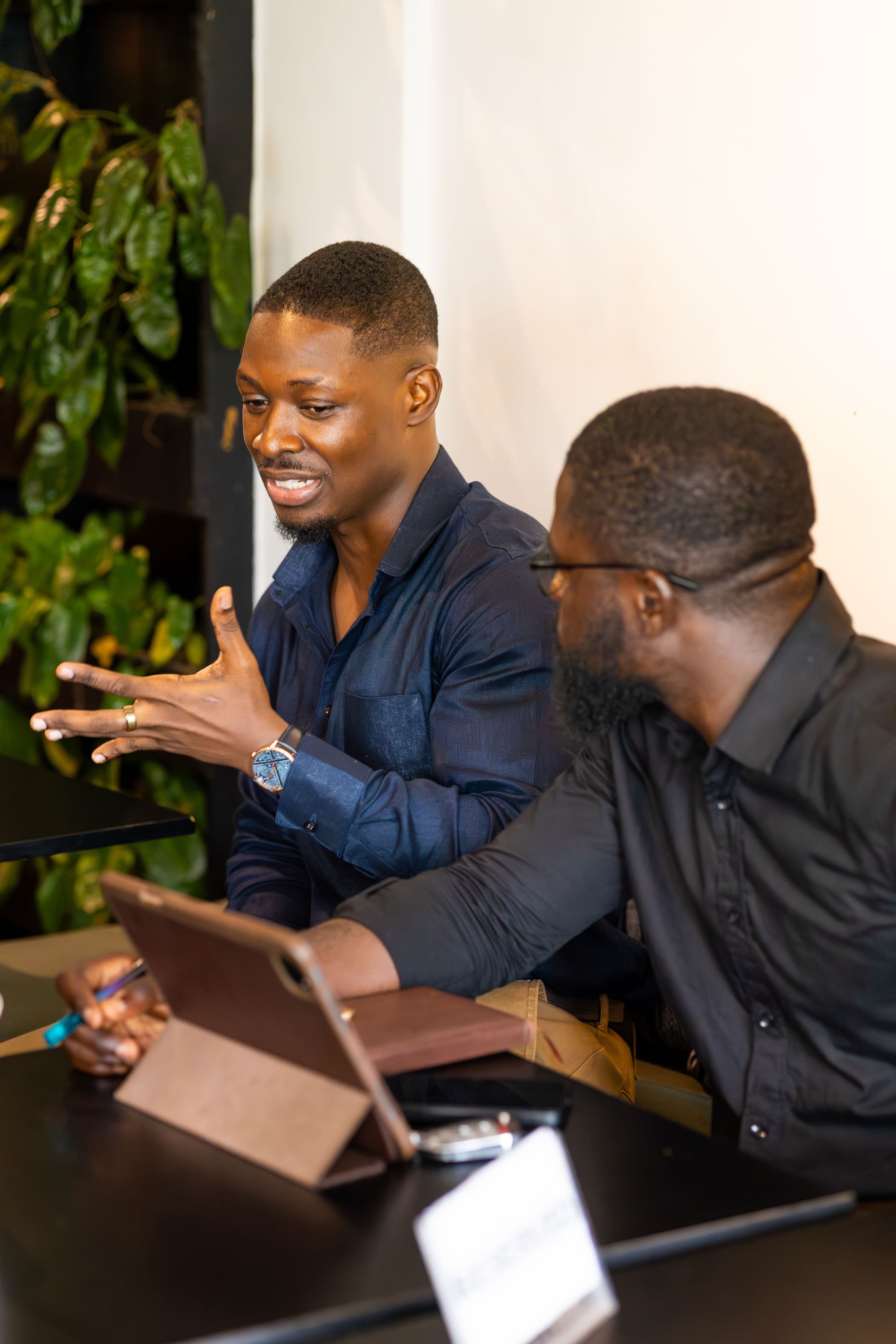 Two attendees in conversation, one explaining, the other reviewing an iPad