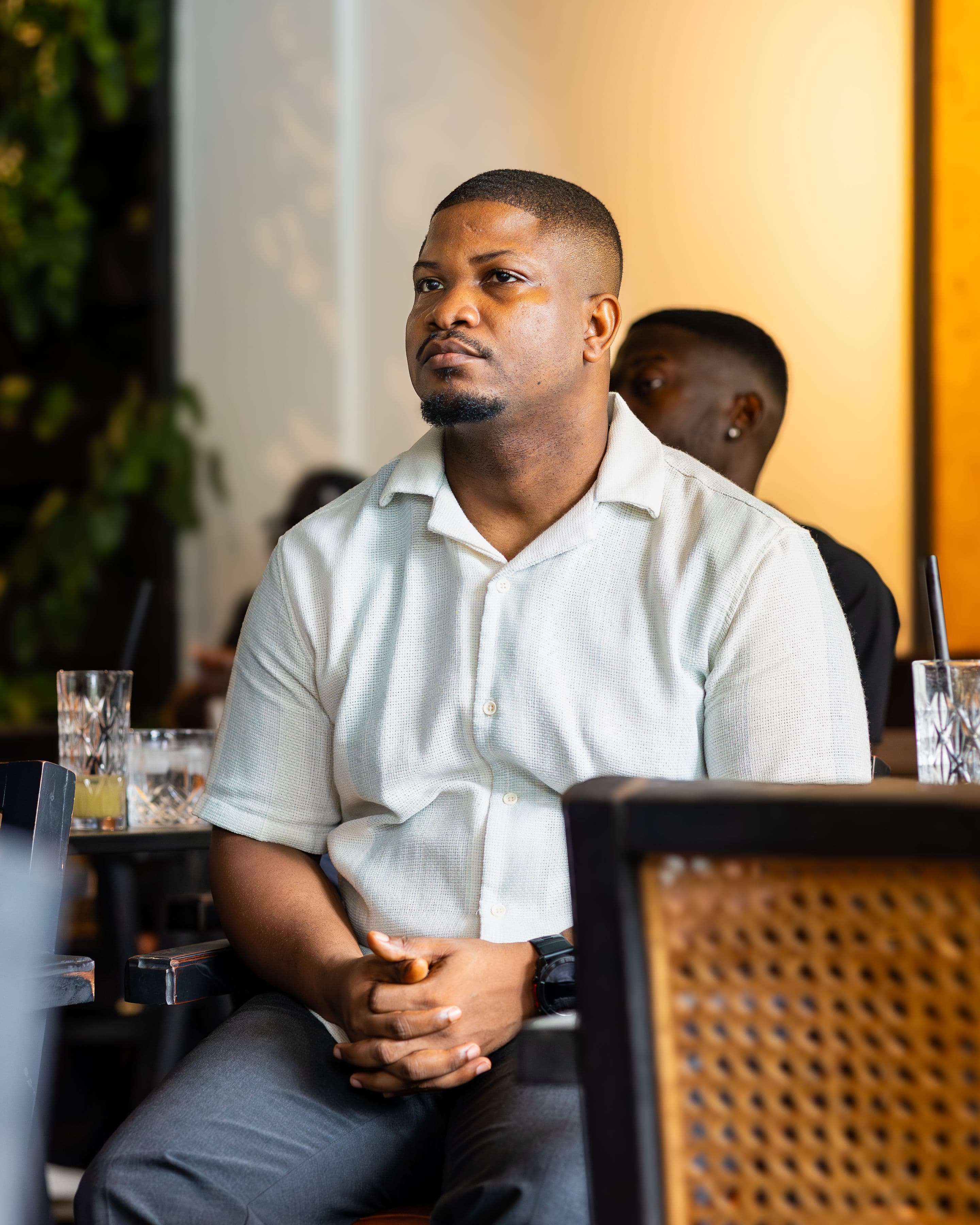 An attendee listening, hands clasped, in warm afternoon light